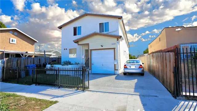a view of a house with a cars park side of a road