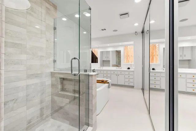 a bathroom with a tub shower sink and mirror