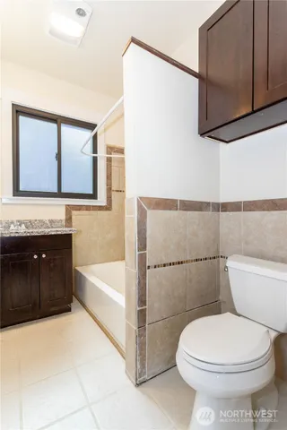 a bathroom with a granite countertop toilet sink and mirror