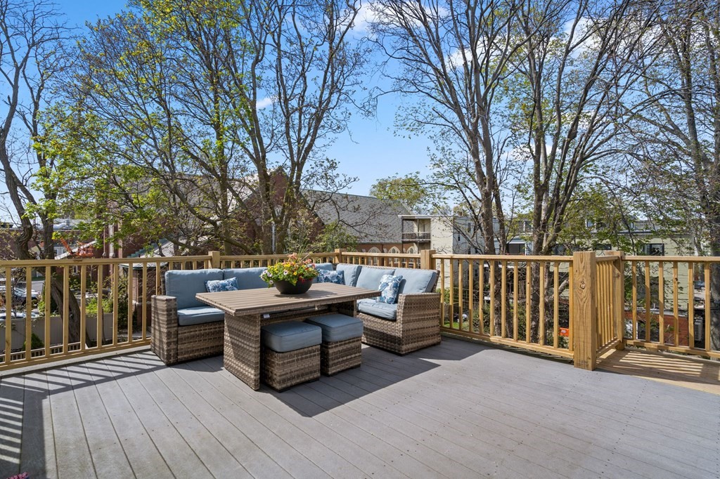 a roof deck with table and chairs and wooden fence