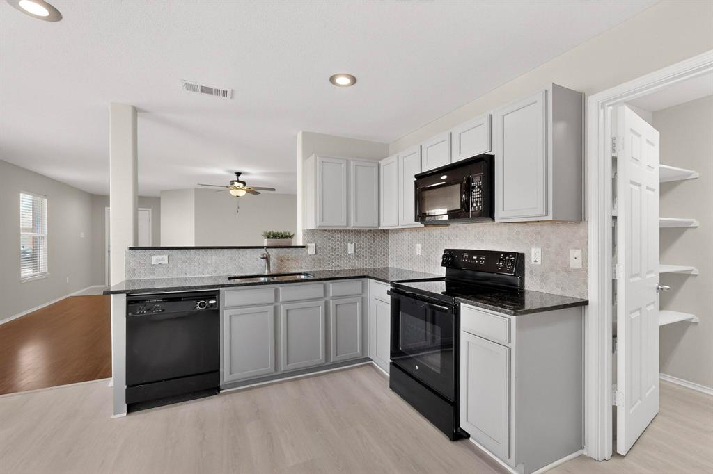 303 Laurel Lane Fate, TX 75087 - Photo 14 of 33 a kitchen with stainless steel appliances granite countertop a stove top oven a sink dishwasher a refrigerator and a microwave oven with wooden floor
