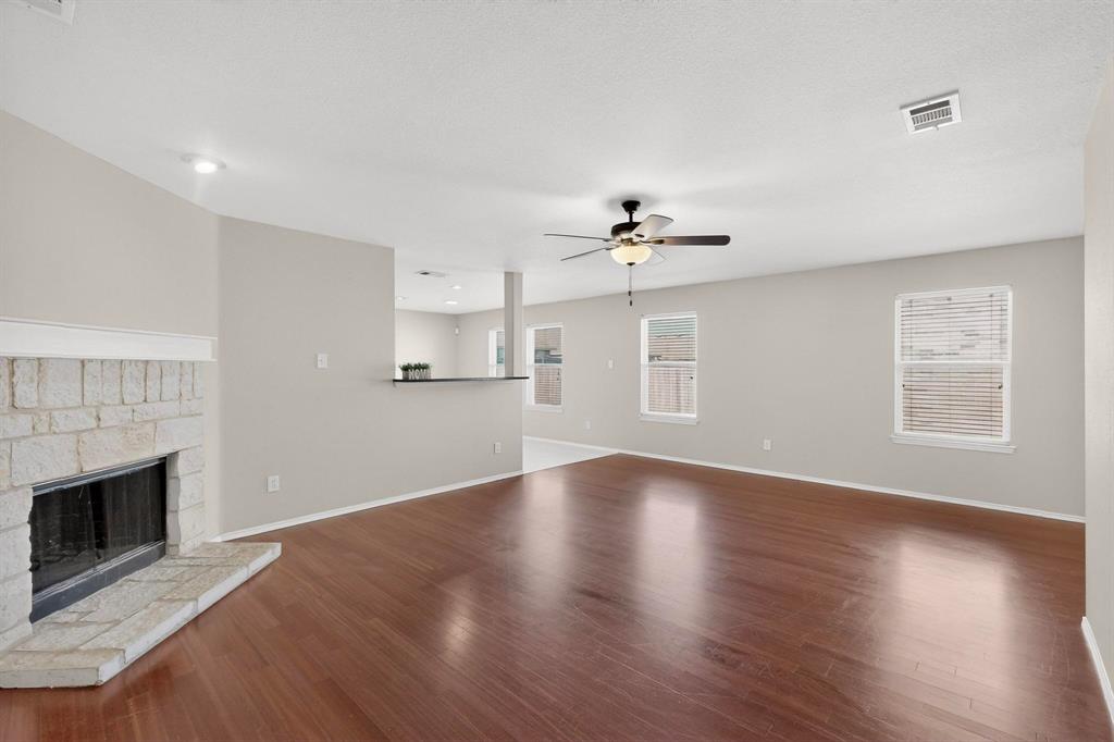 303 Laurel Lane Fate, TX 75087 - Photo 9 of 33 a view of an empty room with a fireplace and wooden floor