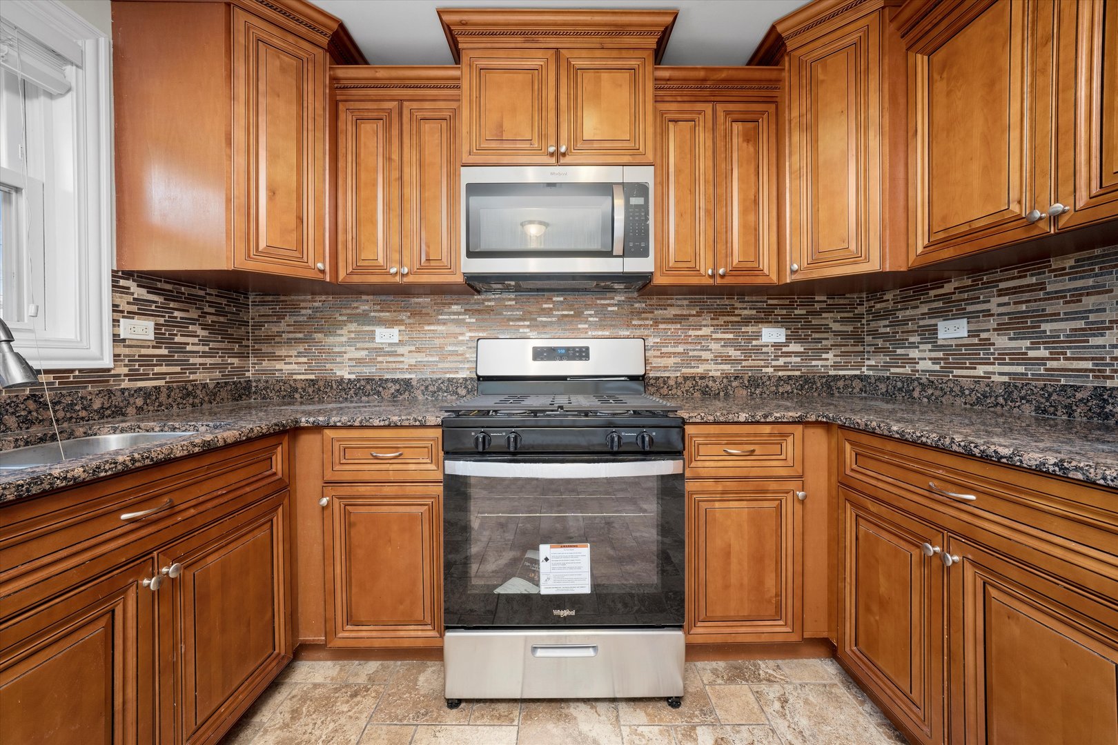 7918 74th Street Bridgeview, IL 60455 - Photo 11 of 26 a kitchen with granite countertop wood cabinets stainless steel appliances and a counter space