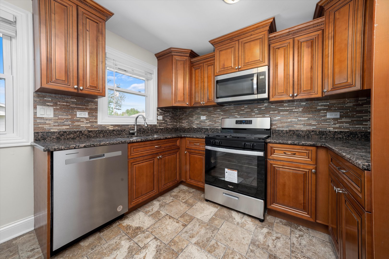 7918 74th Street Bridgeview, IL 60455 - Photo 13 of 26 a kitchen with stainless steel appliances granite countertop a stove sink microwave and cabinets