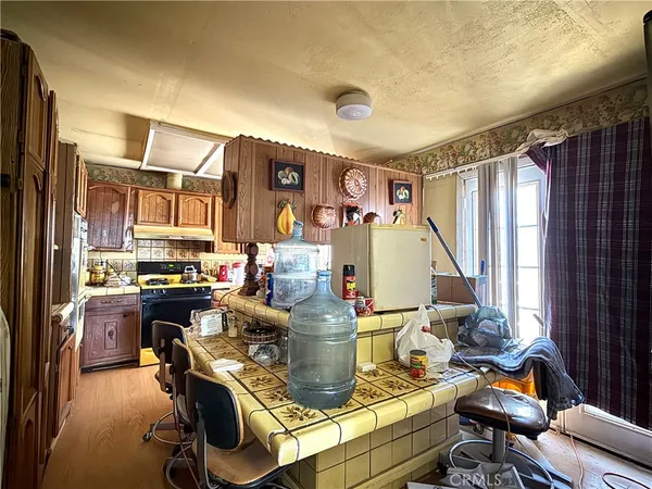 a kitchen with a refrigerator a stove a sink dishwasher and wooden cabinets with wooden floor
