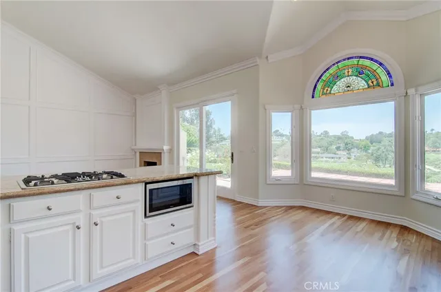 a kitchen with stainless steel appliances a stove a white cabinets and a wooden floor