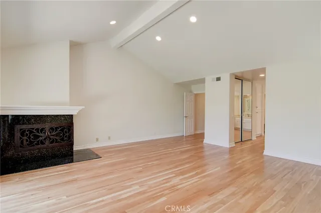 an empty room with wooden floor fireplace and windows