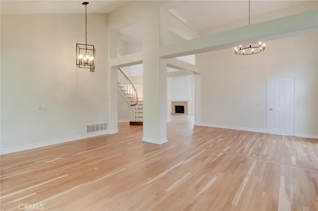 a view of an empty room with wooden floor and windows