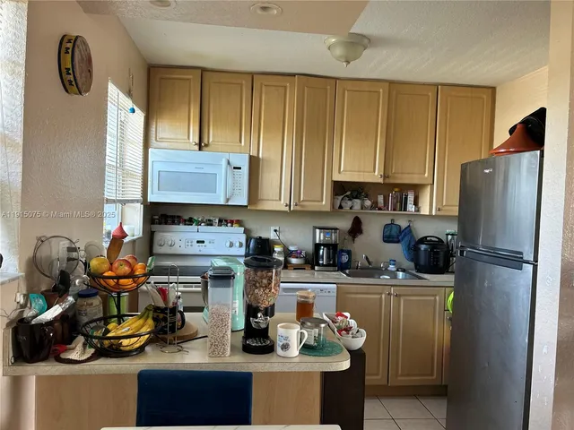 a kitchen with refrigerator a stove a sink and cabinets