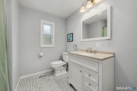a bathroom with a granite countertop toilet a sink and a mirror