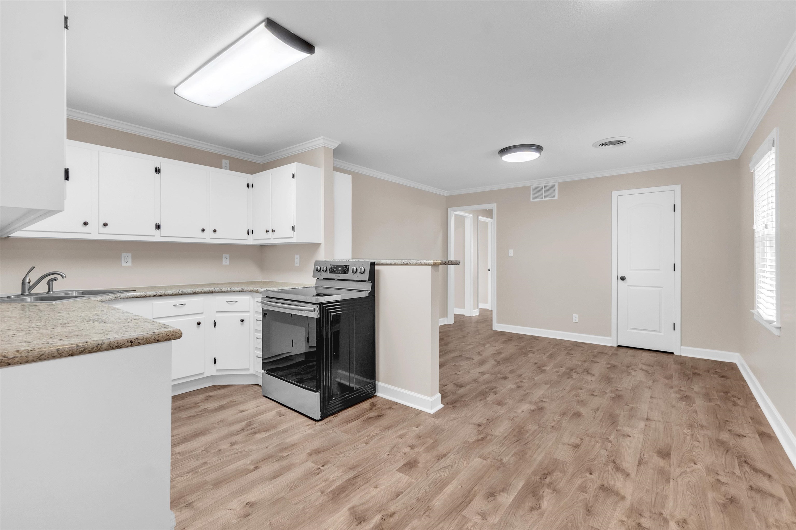 1371 Phillips Road Memphis, TN 38134 - Photo 18 of 35 Kitchen featuring stainless steel range with electric cooktop, white cabinets, light countertops, crown molding, and light wood-style flooring