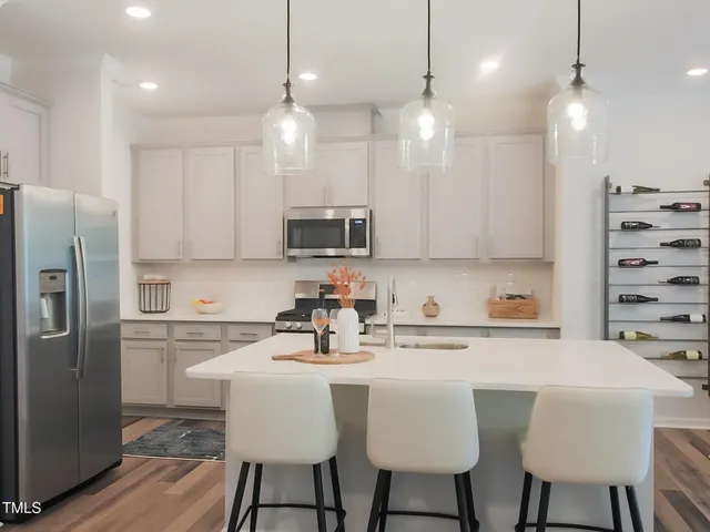 a kitchen with stainless steel appliances a dining table chairs refrigerator and microwave