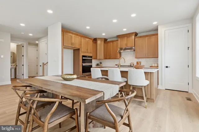 a kitchen with stainless steel appliances kitchen island granite countertop a dining table chairs refrigerator and sink