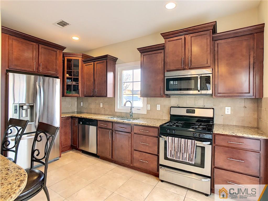 724 Palisade Road Union, NJ 07083 - Photo 5 of 20 a kitchen with stainless steel appliances granite countertop a stove top oven a sink and dishwasher a refrigerator with wooden cabinets