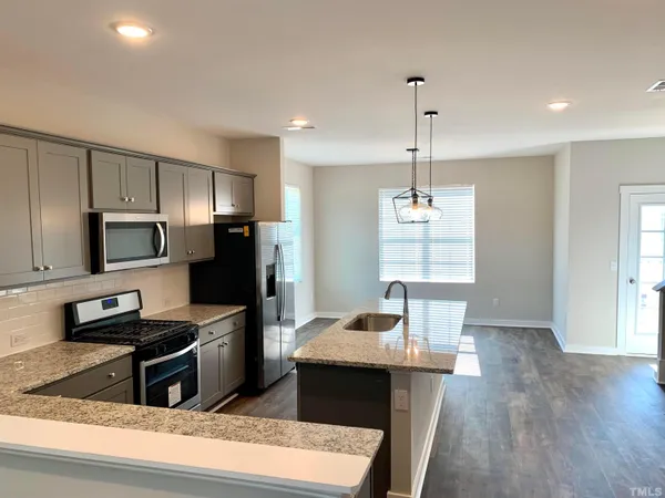 a kitchen with kitchen island a counter space a sink appliances and cabinets