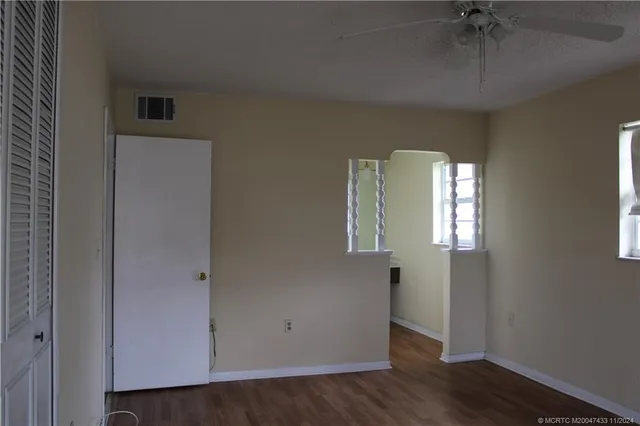 an empty room with wooden floor fan and windows