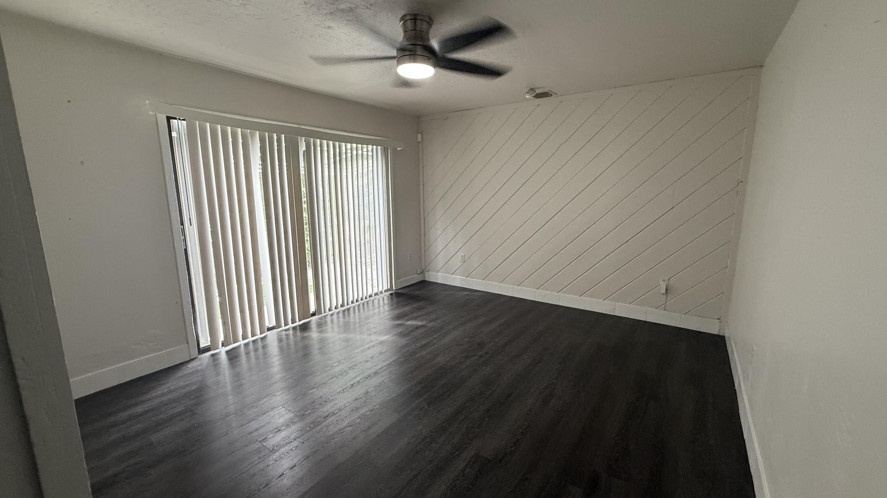 91790 Overseas Highway, Unit BACK Tavernier, FL 33070 - Photo 5 of 13 an empty room with wooden floor chandelier fan and windows