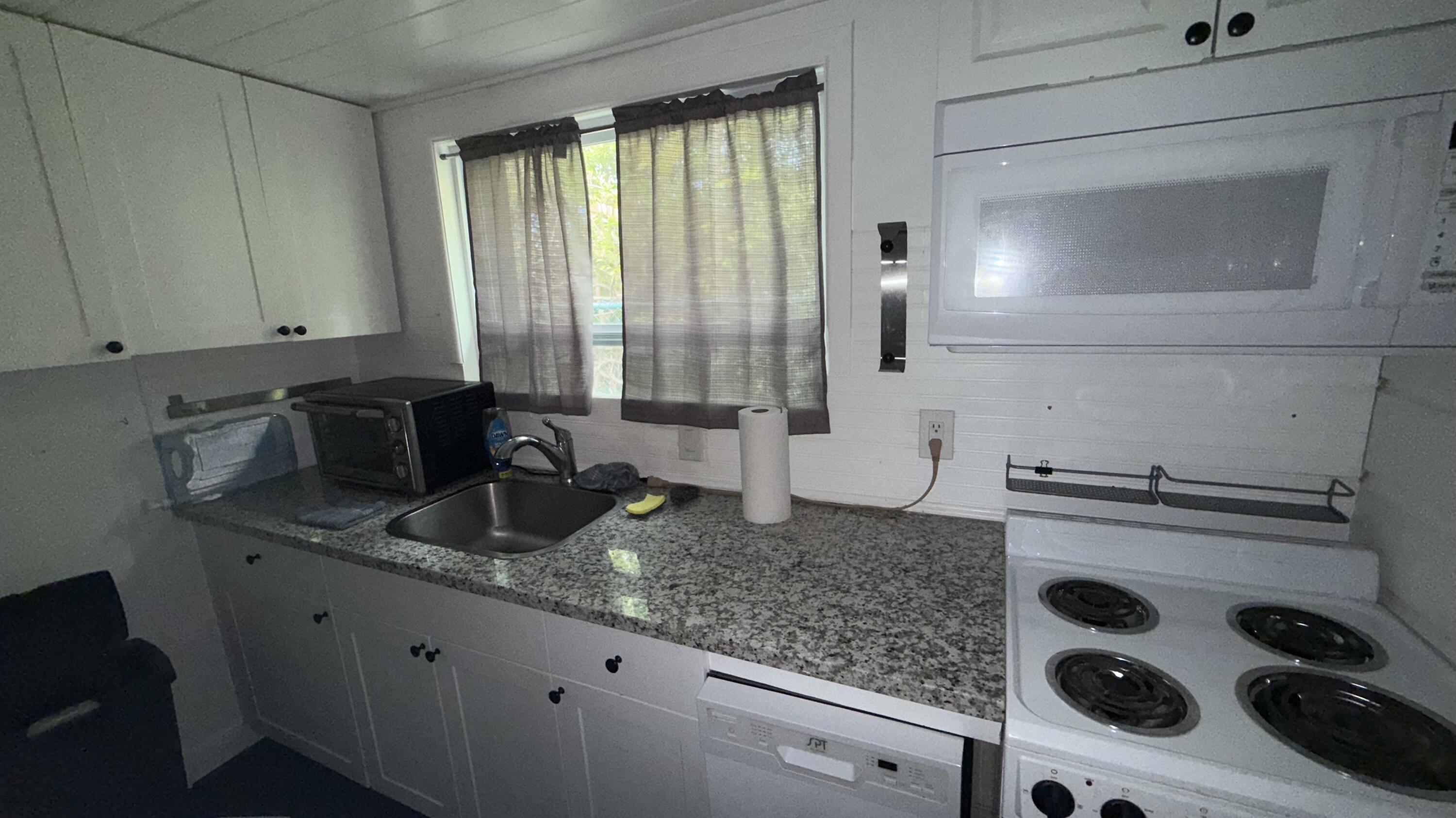 91790 Overseas Highway, Unit BACK Tavernier, FL 33070 - Photo 10 of 13 a kitchen with granite countertop a sink a stove and cabinets