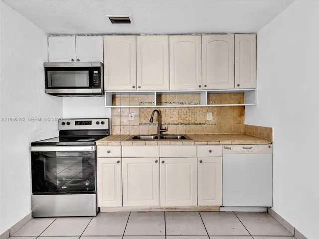 a kitchen with cabinets stainless steel appliances and a sink