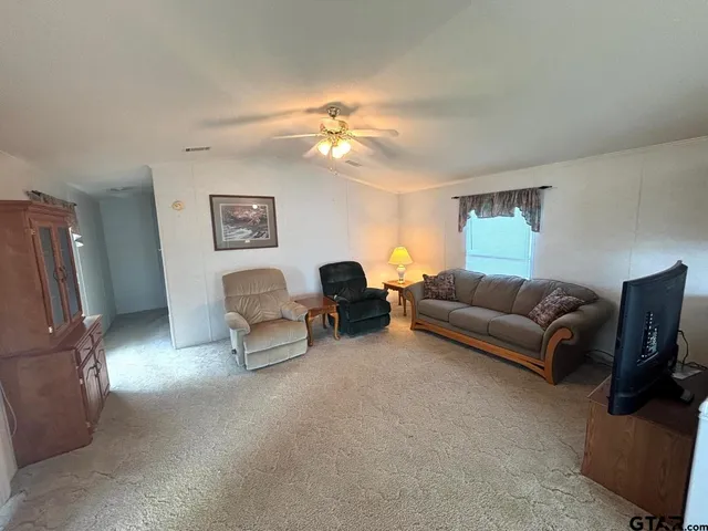 a living room with furniture a ceiling fan and a window