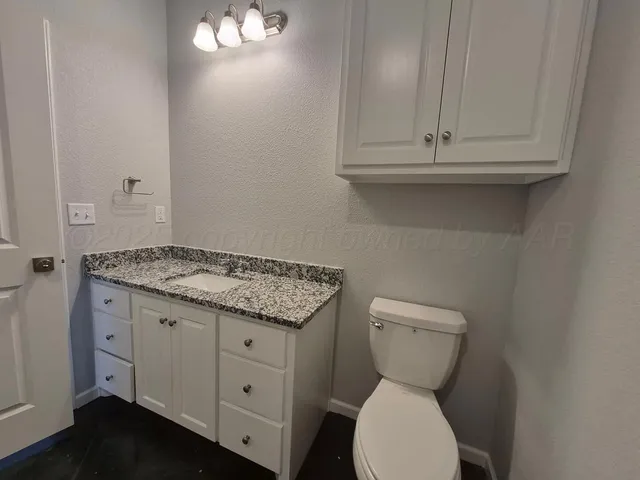 a bathroom with a granite countertop toilet and a sink