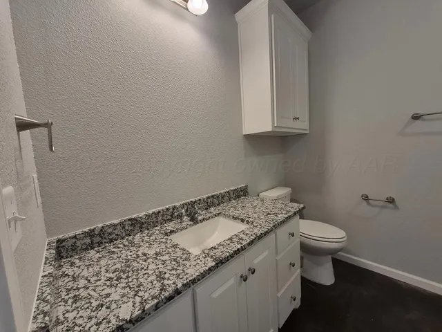 a bathroom with a granite countertop sink a toilet and mirror