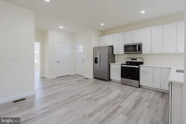 a view of kitchen with stainless steel appliances refrigerator stove microwave and cabinets