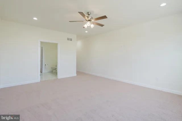 an empty room with windows and chandelier fan