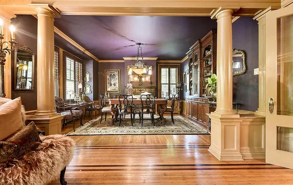a view of a dining room with furniture a chandelier and large windows
