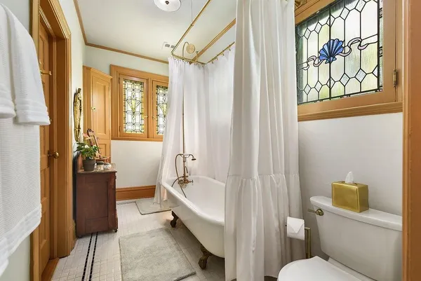 a bathroom with a tub toilet and window