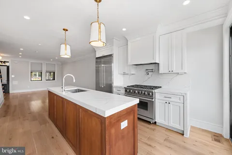 a kitchen with stainless steel appliances granite countertop a sink a stove a refrigerator and a wooden cabinets