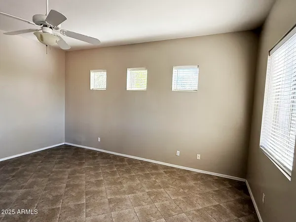 an empty room with windows and chandelier fan