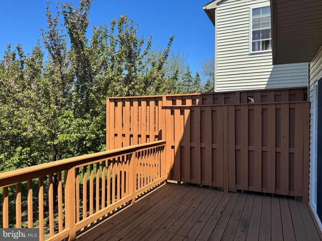 a balcony with wooden floor and trees in the background