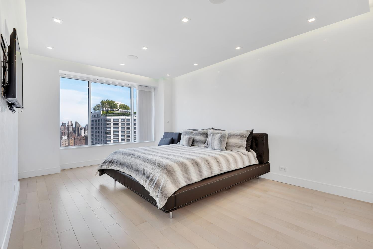 200 East 69th Street, Unit 31A Manhattan, NY 10021 - Photo 12 of 19 a spacious bedroom with a bed and glass door
