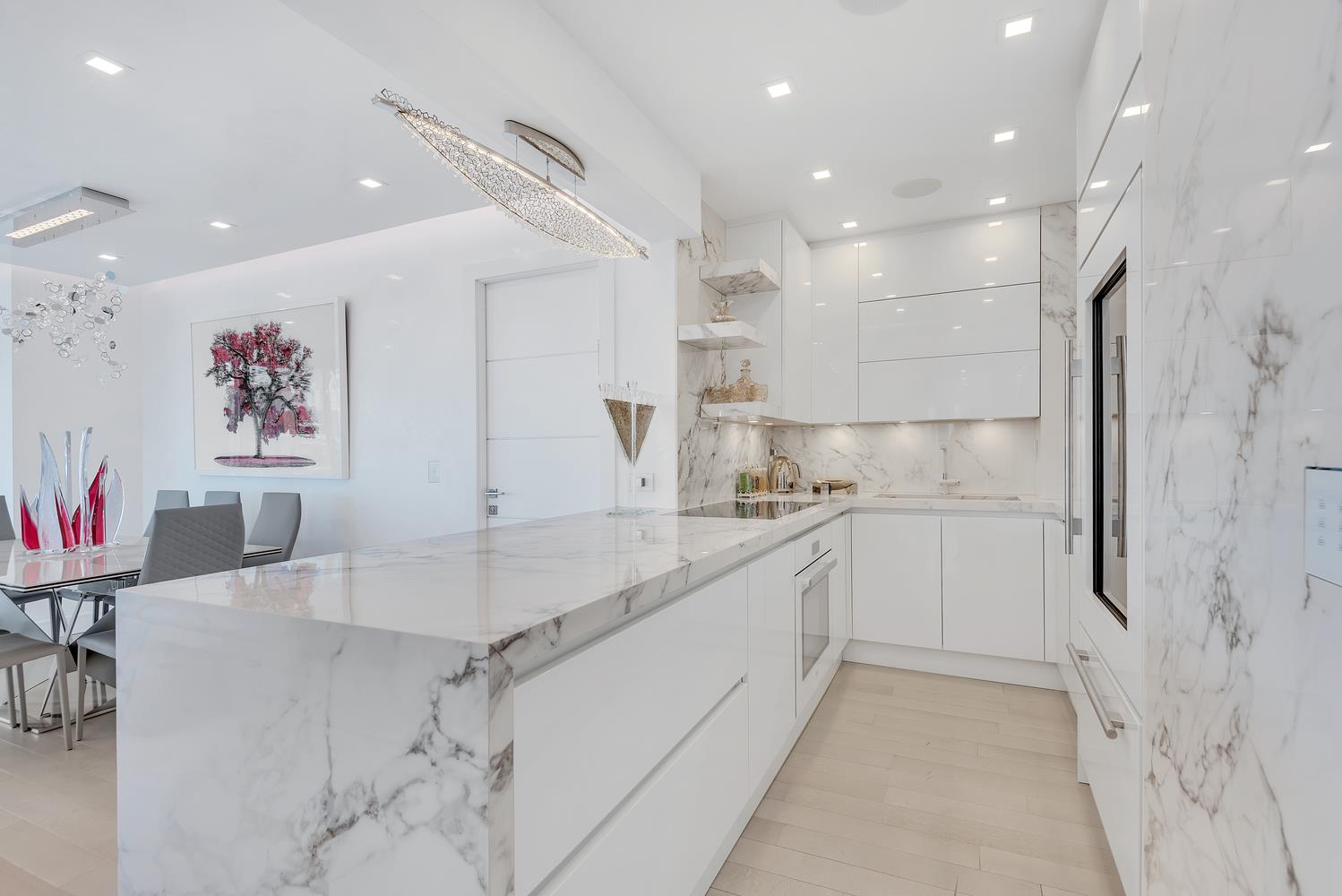 200 East 69th Street, Unit 31A Manhattan, NY 10021 - Photo 7 of 19 a large white kitchen with a refrigerator a sink dishwasher a oven and a dining table with wooden floor