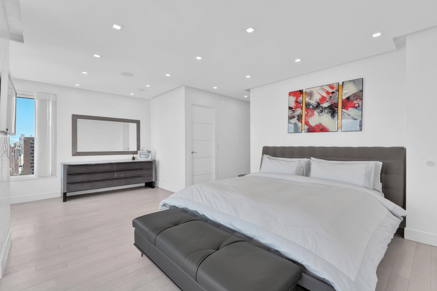 200 East 69th Street, Unit 31A Manhattan, NY 10021 - Photo 8 of 19 a spacious bedroom with a bed and a painting on the wall