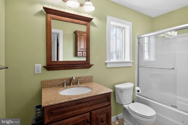 a bathroom with a granite countertop toilet sink and mirror