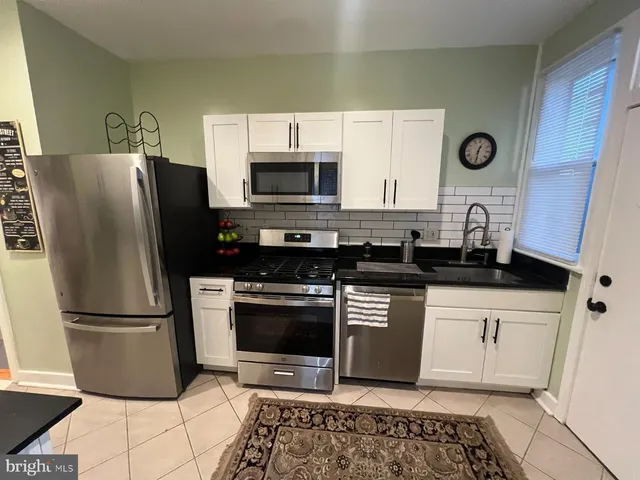 a kitchen with granite countertop a refrigerator and a stove top oven