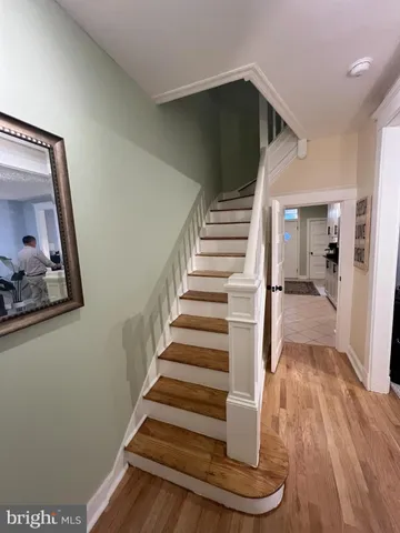 a view of a hallway with wooden floor and a bathroom