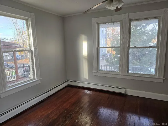 a view of an empty room with wooden floor and a window