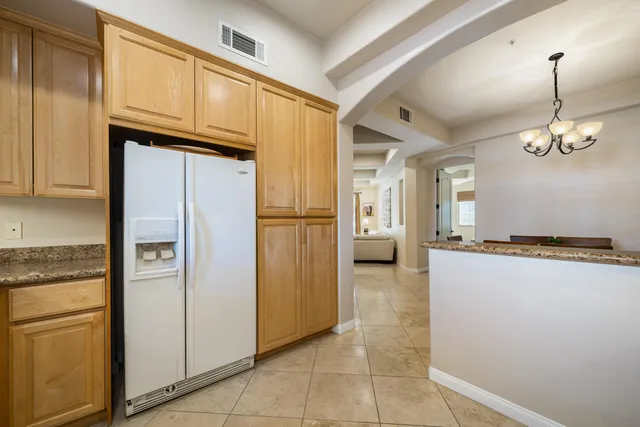 a kitchen with stainless steel appliances granite countertop a refrigerator a oven and white cabinets with wooden floors