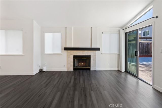 a view of an empty room with wooden floor fireplace and a window