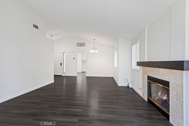a view of an empty room with wooden floor fireplace and a window