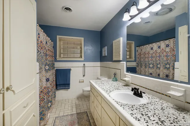 a bathroom with a granite countertop sink a mirror and shower