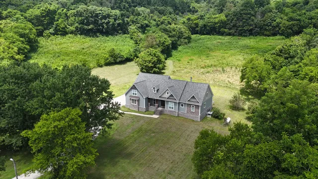 an aerial view of residential houses with outdoor space and trees all around