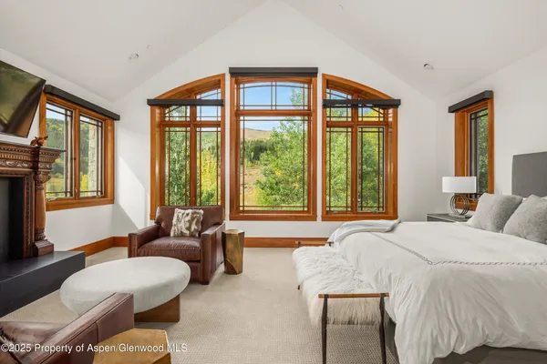 a spacious bedroom with furniture a flat screen tv and a fireplace