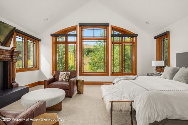 a spacious bedroom with furniture a flat screen tv and a fireplace