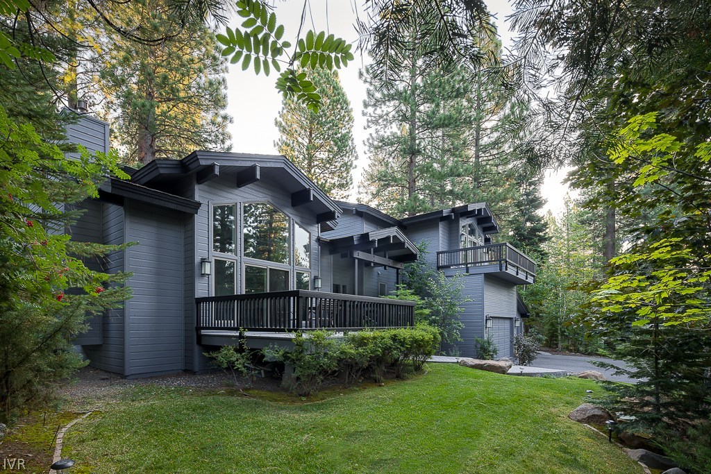 a view of a wooden house with a yard and large trees