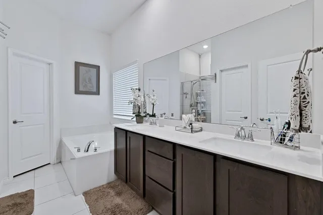 a bathroom with a double vanity sink a mirror and a bathtub