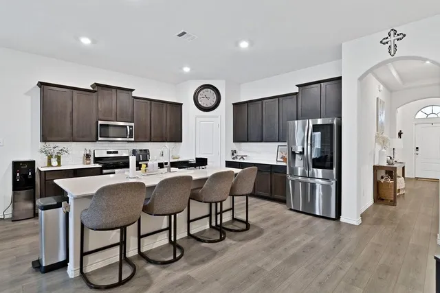 a kitchen with stainless steel appliances granite countertop a stove top oven a refrigerator a sink and chairs